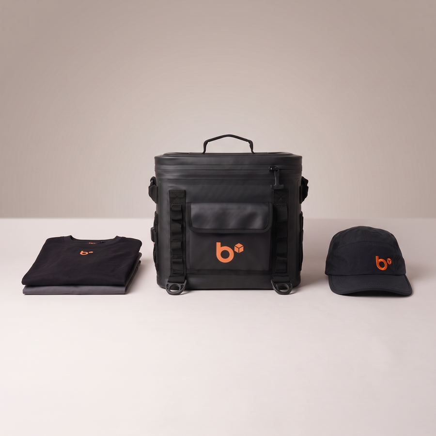 THE CUBE insulated lunchbox front-on with folded black and grey work tees and b.cubed work cap